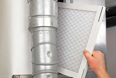 HVAC furnace technician replacing air filter.